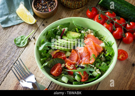 Menu de régime, la nourriture végétalienne. Salade saine avec le quinoa, la roquette, les tomates, le saumon et d'avocat sur la table rustique. Banque D'Images