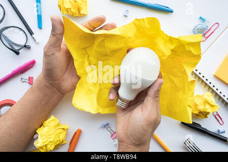 Inspiration créativité concepts avec lightbulb en boule chiffonnée papier sur les hommes de main.Des idées d'entreprise et solution human performance.vue d'en haut Banque D'Images