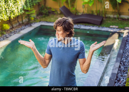 Homme choisit des produits chimiques pour la piscine. Piscine publique et de l'équipement avec les produits de nettoyage chimiques et outils Banque D'Images