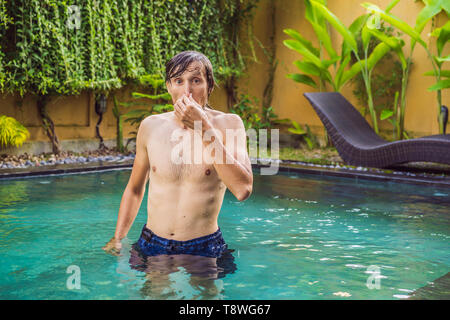 Jeune homme avec dégoût sur son visage, nez pincées ça pue, très mauvaise odeur dans la piscine à cause de produits chimiques pour la piscine. Faciale émotion négative Banque D'Images