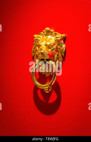 Knoker sous la forme d'un lion d'or sur le fond de la surface rouge de la porte. Banque D'Images