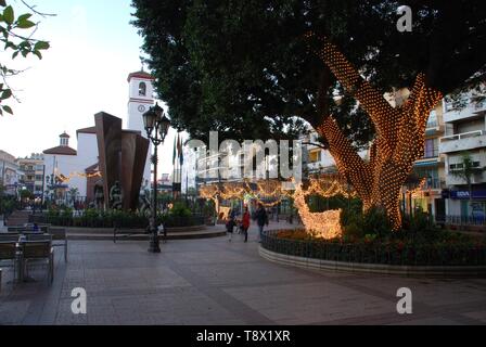 Fontaine de la place de la Constitution (Plaza de la Constitucion) au crépuscule avec l'Église à l'arrière, Fuengirola, Espagne. Banque D'Images