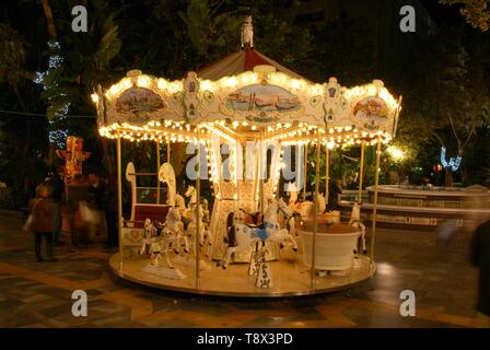 Carrousel pour enfants éclairés la nuit dans le Parque de la Alameda, Marbella, Costa del Sol, la province de Malaga, Andalousie, espagne. Banque D'Images