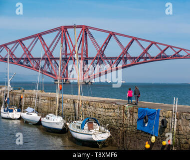 South Queensferry, Ecosse, Royaume-Uni, 15 mai 2019. UK : météo ensoleillée magnifique journée chaude le long de la côte du Firth of Forth, à l'emblématique Forth Rail Bridge. Les gens à pied sur la jetée du port Banque D'Images