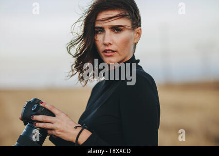 Photographe professionnel pendant une séance photo en extérieur. Jeune femme en tenue décontractée une photo appareil photo à l'extérieur. Banque D'Images