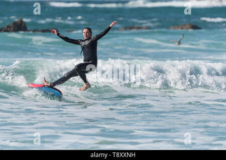 Une femme tomber de sa planche de surf dans une mer couleur de jade dans Fistral à Newquay en Cornouailles. Banque D'Images