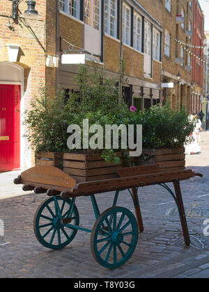 Jardinières en bois rempli de belles plantes et fleurs sur un panier en bois rétro / wagon sur une rue, à l'extrémité ouest de Londres près de Covent Garden Market. Banque D'Images