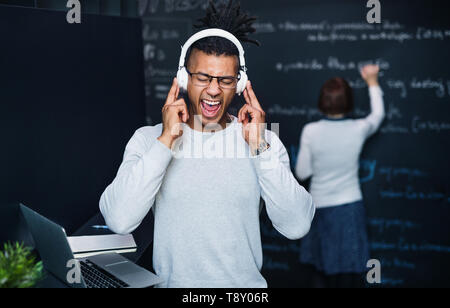 Un jeune homme avec un casque dans Office, écouter de la musique. Banque D'Images