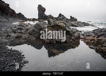 Rock formations sur la plage de Djúpalónssandur, l'Islande se reflétant dans l'eau. Banque D'Images