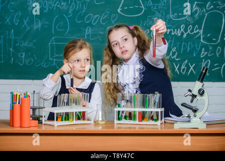 Nous aimons la science. Les enfants de l'école performing experiment in science classroom. Les petites filles scientifiques holding test tubes à leçon de sciences naturelles. Laboratoire de sciences pour l'école et l'éducation. Banque D'Images