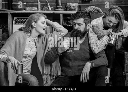 Les amis passent et voyages à l'intérieur confortable. Homme et femmes sur visages heureux de discuter et de boire du vin. Les amis de s'amuser, parler et boire des boissons chaudes dans un intérieur en bois. Soulmates concept. Banque D'Images