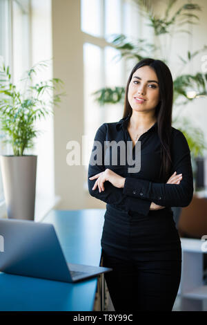 Portrait of businesswoman standing avec succès à son bureau. Banque D'Images