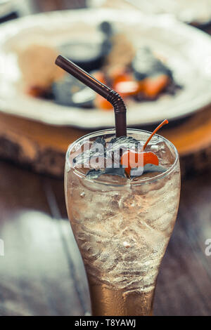 Verre de glace thé noir avec cerise sur le dessus verre pour se rafraîchir sur la table arrière-plan flou dessert Banque D'Images