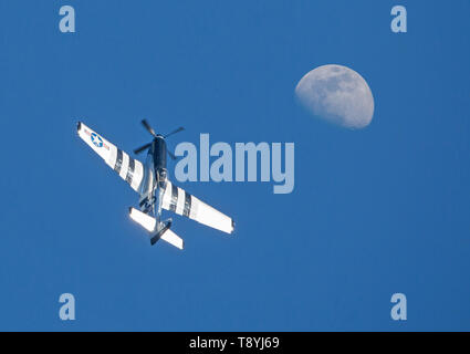 Un avion de chasse P-51 Mustang effectue un voyage tour dans ciel bleu profond sous une Lune gibbeuse. Banque D'Images