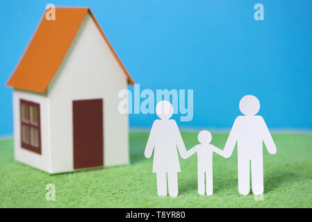 Coupe papier de famille avec maison sur fond d'herbe verte Banque D'Images