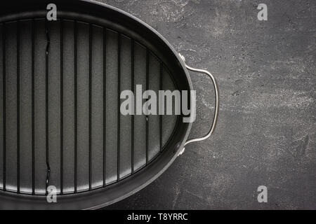 Plat de cuisson antiadhésif gris vide avec des poignées sur la surface de pierre sombre. Contexte culinaire. Banque D'Images