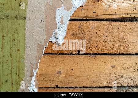 Vieux mur de plâtre en démolition avec panneaux en bois derrière Banque D'Images