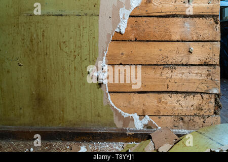 Vieux mur de plâtre en démolition avec panneaux en bois derrière Banque D'Images