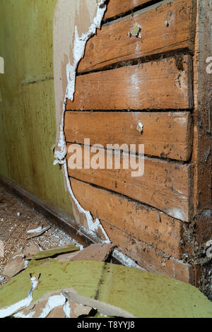 Vieux mur de plâtre en démolition avec panneaux en bois derrière Banque D'Images