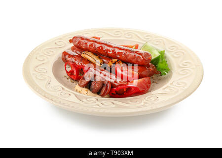 Plaque avec de délicieuses saucisses grillées et légumes sur fond blanc Banque D'Images