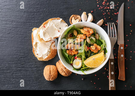 Délicieux salade fraîche avec les noix dans le bol sur la table sombre Banque D'Images