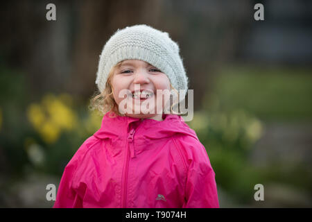 Petite fille dans hat pulling faces in garden Banque D'Images