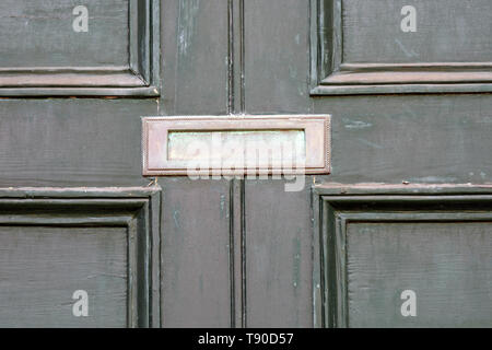 Vieille porte avant vert de maison victorienne, dans état de délabrement avec peinture qui s'écaille et laiton terni heurtoir lion, lettre fort, bouton et trou de serrure. Banque D'Images