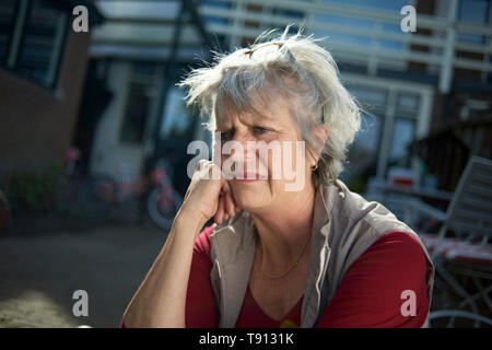 Personnes âgées riches caucasian woman assis dehors dans son jardin à savourer une tasse de thé tout en lisant un magazne en plein soleil du printemps Banque D'Images