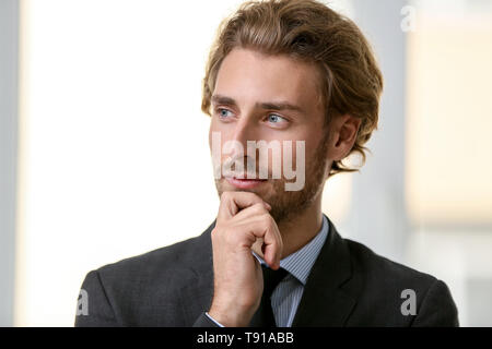 Portrait de jeune homme pensif sur fond clair Banque D'Images