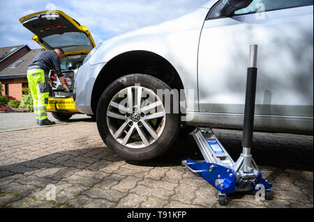 03 mai 2019, Basse-Saxe, Wolfenbüttel : une voiture VW est levé pour une réparation d'un pneu, alors que la répartition de l'ADAC helper recherche des outils dans sa malle. Photo : Christophe Gateau/dpa Banque D'Images