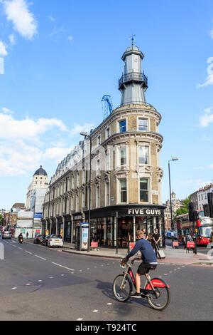 Un cycliste sur un vélo Santander passe le phare, à l'origine un bar à huîtres, maintenant un burger restaurant Five Guys, King's Cross, Londres, Royaume-Uni, 2019 Banque D'Images