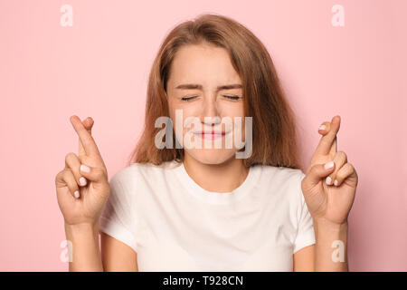 Portrait d'une jeune femme avec les doigts croisés sur un fond de couleur Banque D'Images