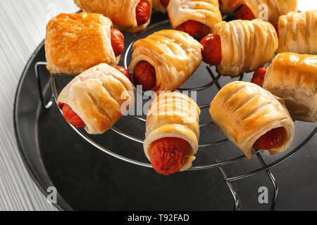 Des petits pains à saucisse savoureuse sur grille de refroidissement, gros plan Banque D'Images