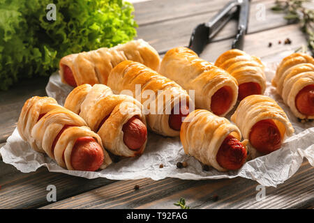 Des petits pains à saucisse savoureuse sur table en bois Banque D'Images