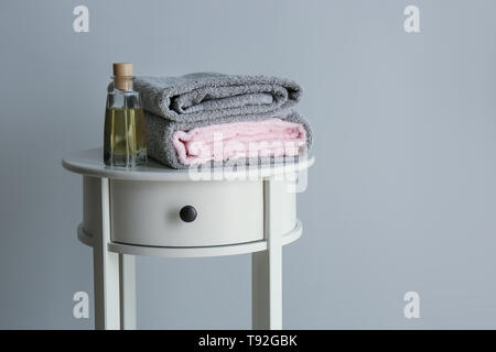 Pile de serviettes propre et doux et bouteille de cosmétiques sur table lumineuse Banque D'Images