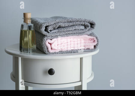 Pile de serviettes propre et doux et bouteille de cosmétiques sur table lumineuse Banque D'Images