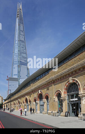 Les unités de vente au détail récemment rénové in ornate arches sous la Station London Bridge, le St Thomas Street, London, UK. Le Shard visible au-delà. Banque D'Images