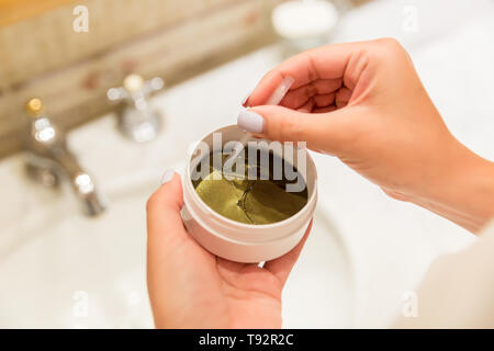 Fille avec une pincette sort eye patches à partir de la boîte de dialogue. Matin spa concept. Banque D'Images