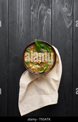 Mung Dhal avec épinards vert à table en bois noir. Moong Dal - la cuisine indienne, le curry. Plat végétarien avec zira et la coriandre . Vue supérieure verticale Banque D'Images