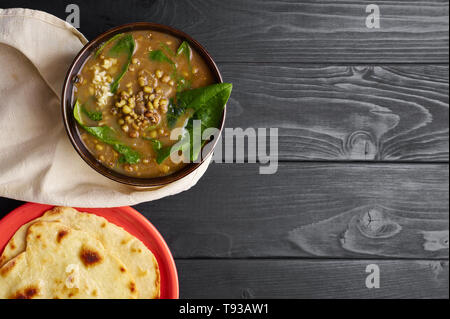 Mung Dhal avec épinards vert à table en bois noir. Moong Dal - la cuisine indienne, le curry. Plat végétarien avec chapati.top view Copy Space Banque D'Images