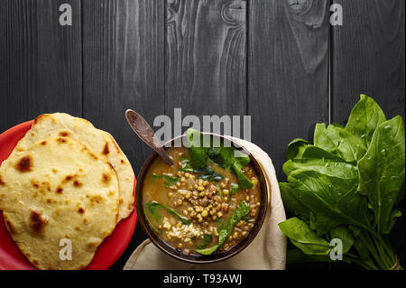 Mung Dhal avec épinards vert et Chapati à table en bois noir. Moong Dal - la cuisine indienne, le curry. Plat épicé végétarien.top view Copy Space Banque D'Images