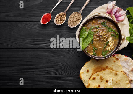 Mung Dhal, épinards, Chapati, d'ail et d'épices à table en bois noir. Moong Dal - la cuisine indienne, le curry. Plat épicé végétarien.top view Copy Space Banque D'Images