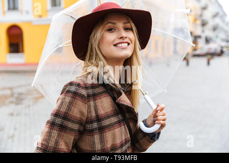 Très belle jeune femme blonde élégante portant un manteau la marche à l'extérieur, holding umbrella Banque D'Images