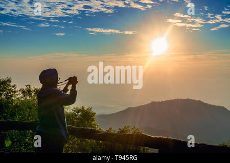 Locations de tourisme et voyage. Un touriste de prendre photo de beau soleil se lever au paysage de montagne à sun rise time avec appareil photo mirrorless à Doi Ang Kha Banque D'Images