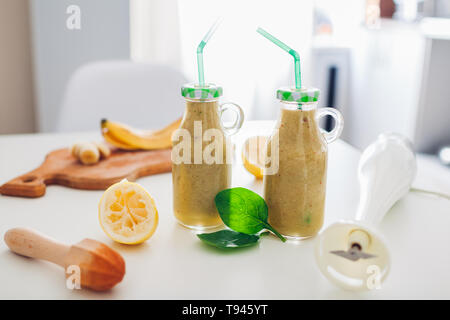 Bouteilles avec des épinards et banana smoothie d'ingrédients sur une table de cuisine. Régime de detox en bonne santé Banque D'Images