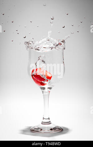 Boire un soda splash photographié comme une fraise tombe dans le verre. Banque D'Images