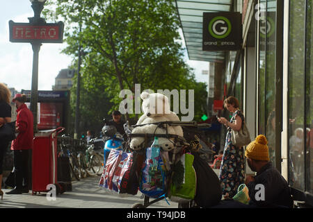 Un sans-abri assis à l'extérieur d'une boutique à proximité de la station de métro dans le centre-ville de Paris avec les gens qui passent par Banque D'Images