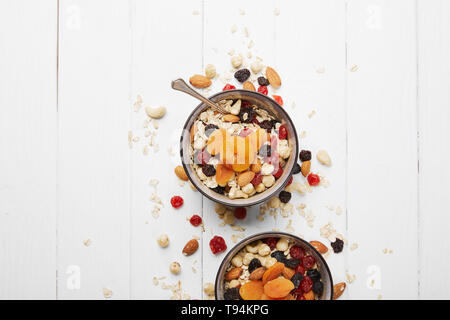 Vue de dessus de la pétanque avec du muesli, des abricots séchés et les fruits et les écrous pour le petit-déjeuner avec des ingrédients sur tableau blanc Banque D'Images