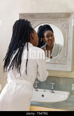 Pretty young african american woman doing her routine du matin devant le miroir de salle de bains Banque D'Images
