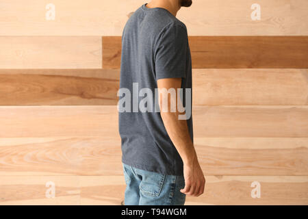 Jeune homme en t-shirt élégant sur fond de bois Banque D'Images